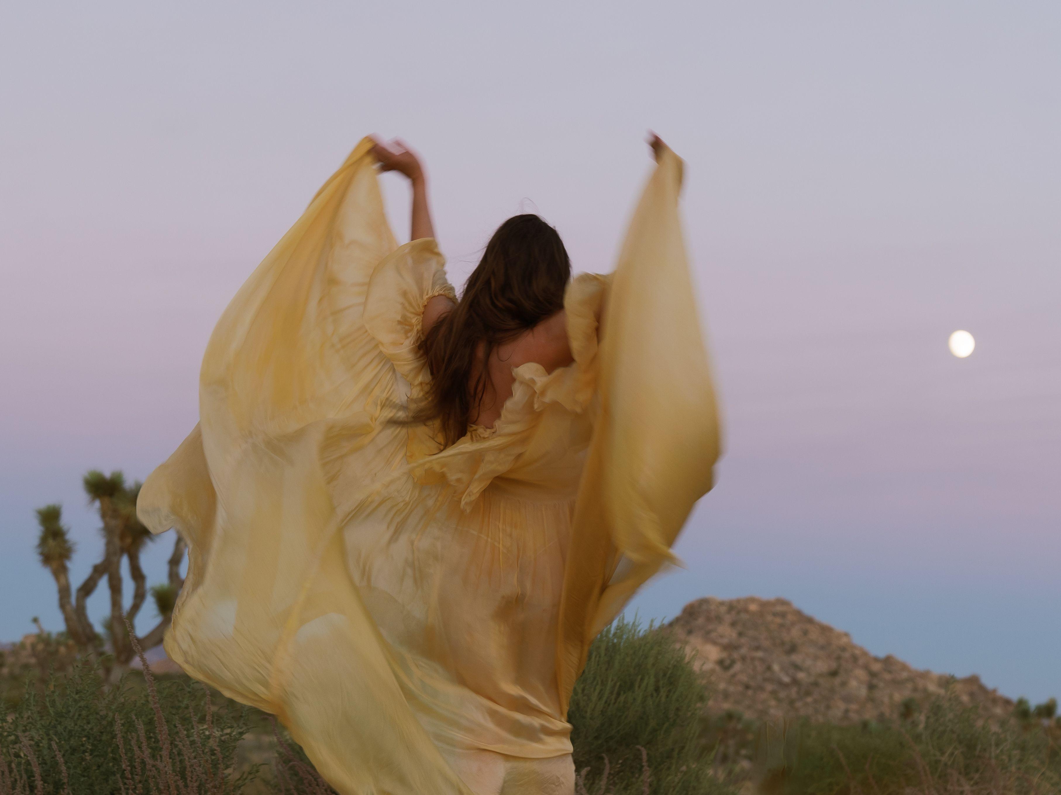 A woman in a flowing golden dress dancing under the full moon